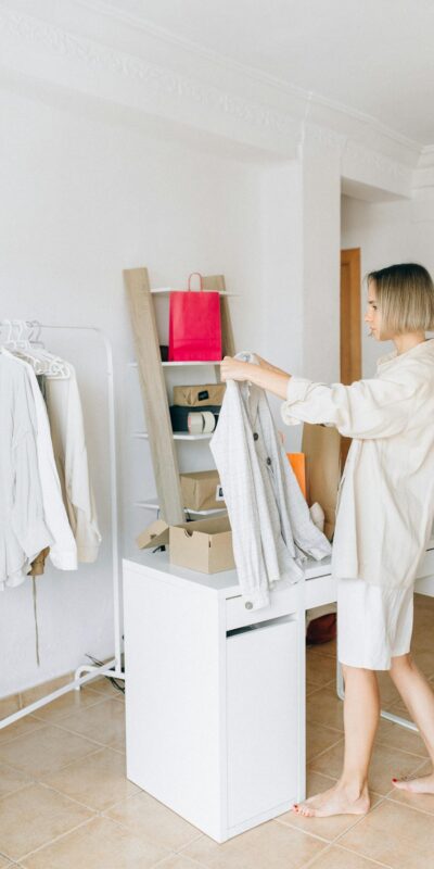 Woman sorting garments in a modern apartment, showcasing a clean, minimalist lifestyle.