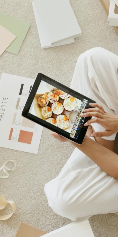 Woman using tablet surrounded by design tools and gift box, showcasing creativity and online work.